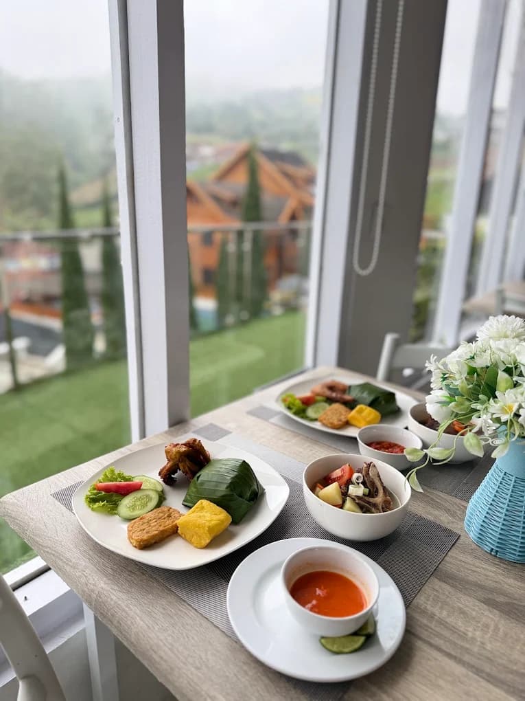 Hidangan sarapan khas Nusantara di meja dekat jendela dengan pemandangan Darajat